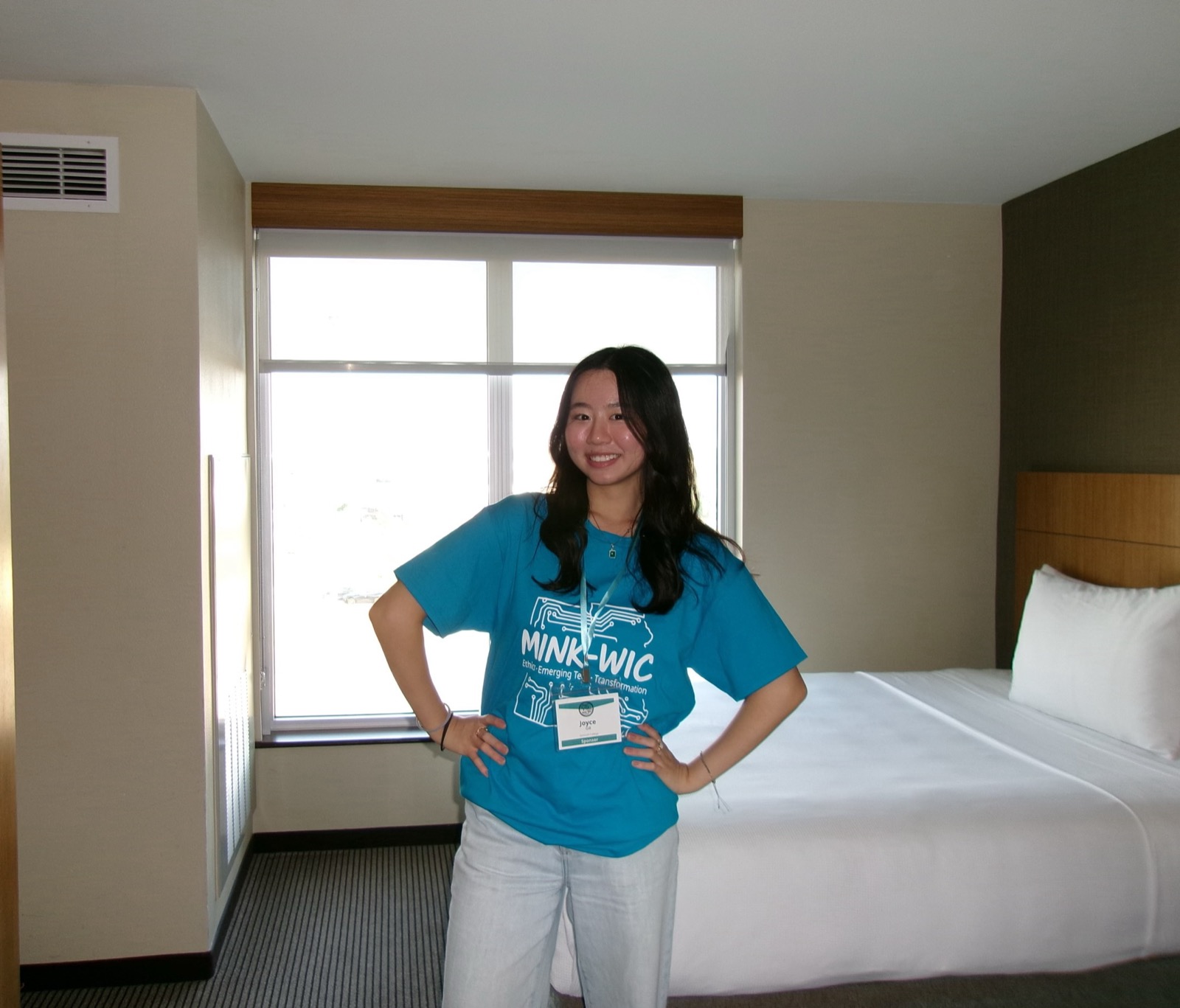 Joyce standing in front of her hotel at ACM-W MINK-WIC in a blue MINK-WIC t-shirt