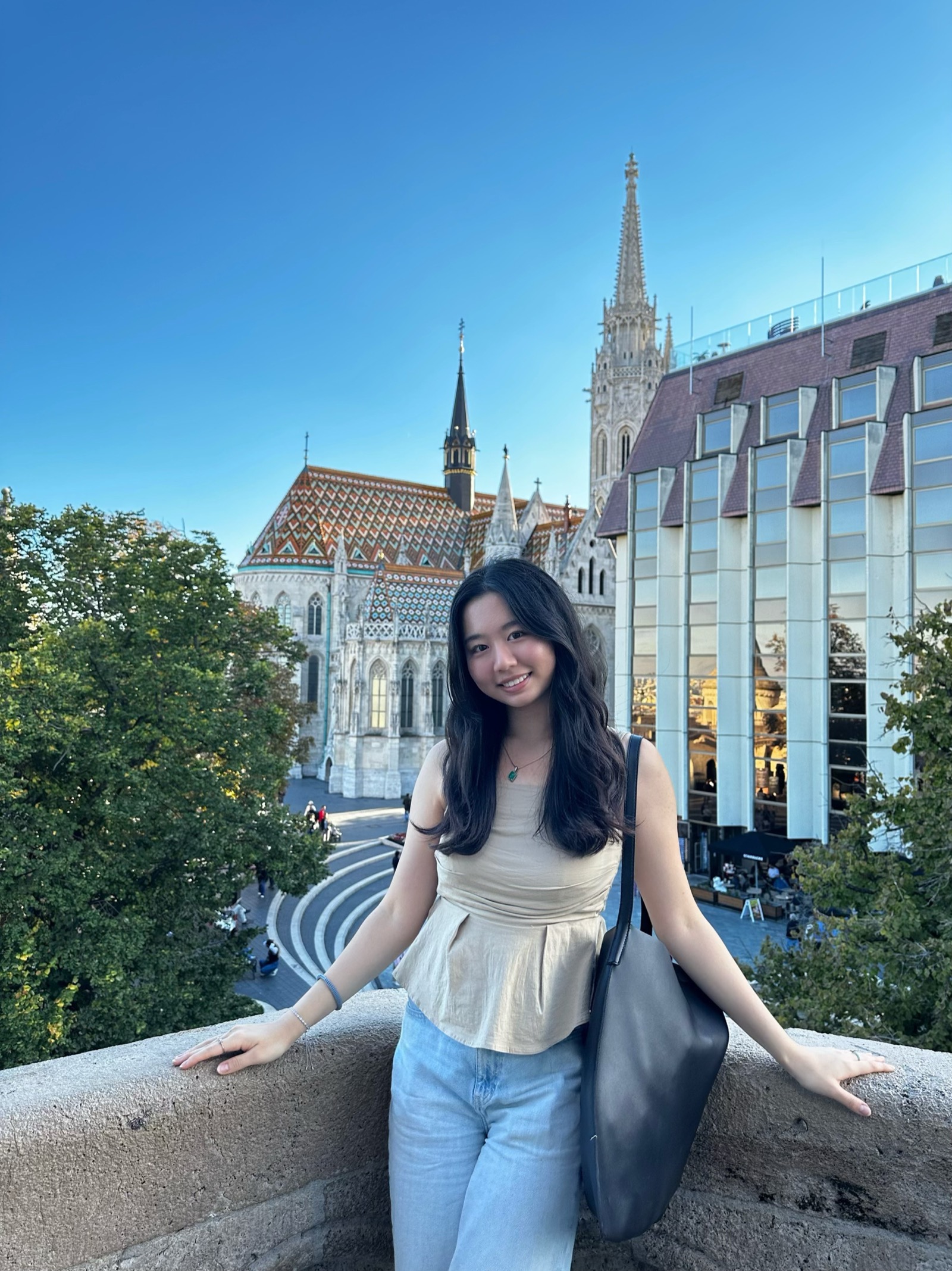 Joyce standing in front of the Matthias Church in Budapest, Hungary in a beige top and blue jeans